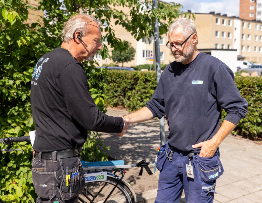 Medarbetare från Sanitet och Spolteknik skakar hand med kund utomhus.